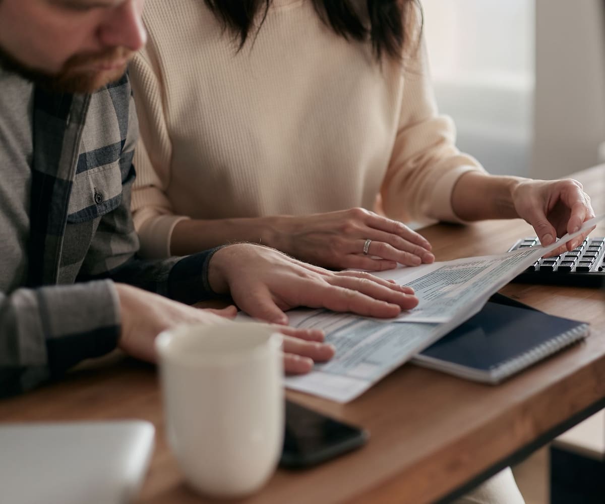 Couple examinant le budget d'une maison à vendre avec documents et calculatrice