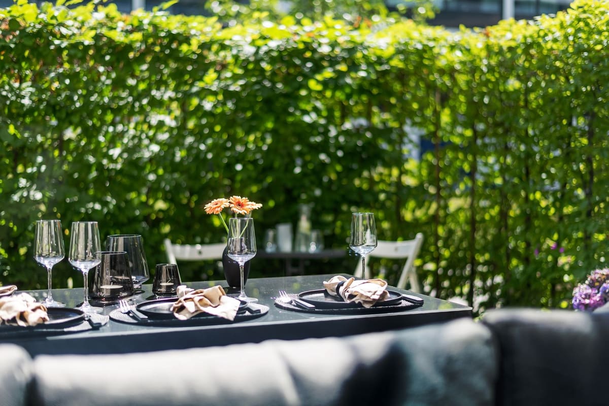 Salon de jardin abrité par un brise-vue en bois avec coussins rangés