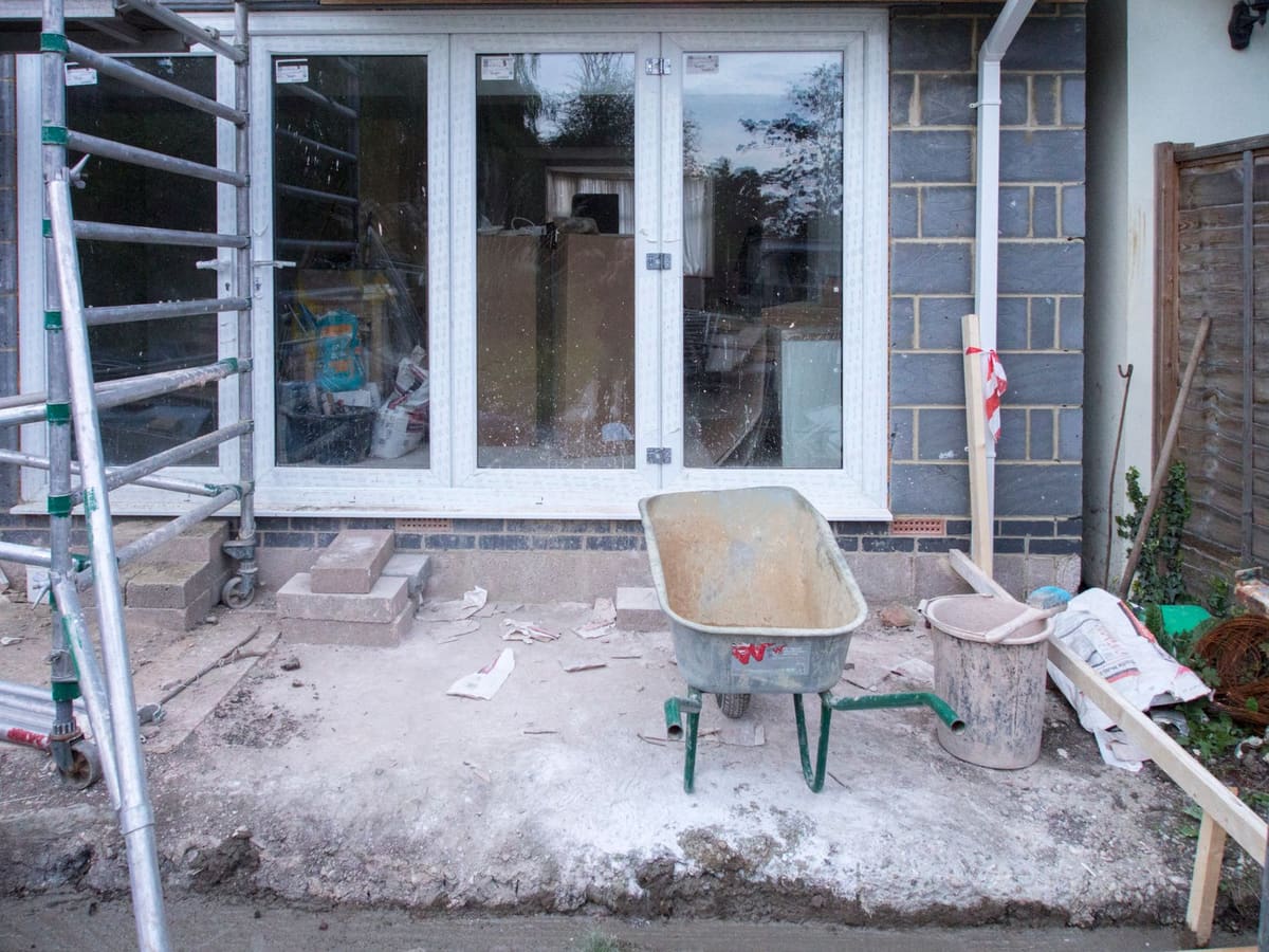 Chantier d'extension maison en parpaing avec fondations et murs en cours de montage